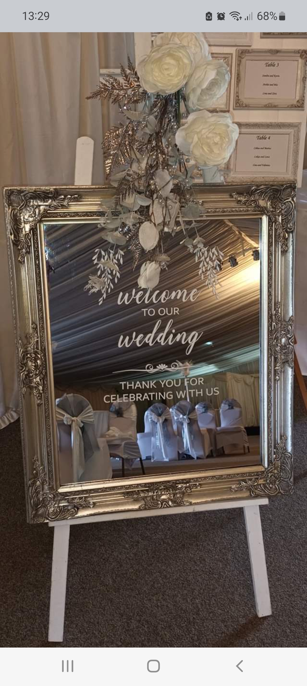 Silver welcome mirror for winter wedding, on an easel with white flowers