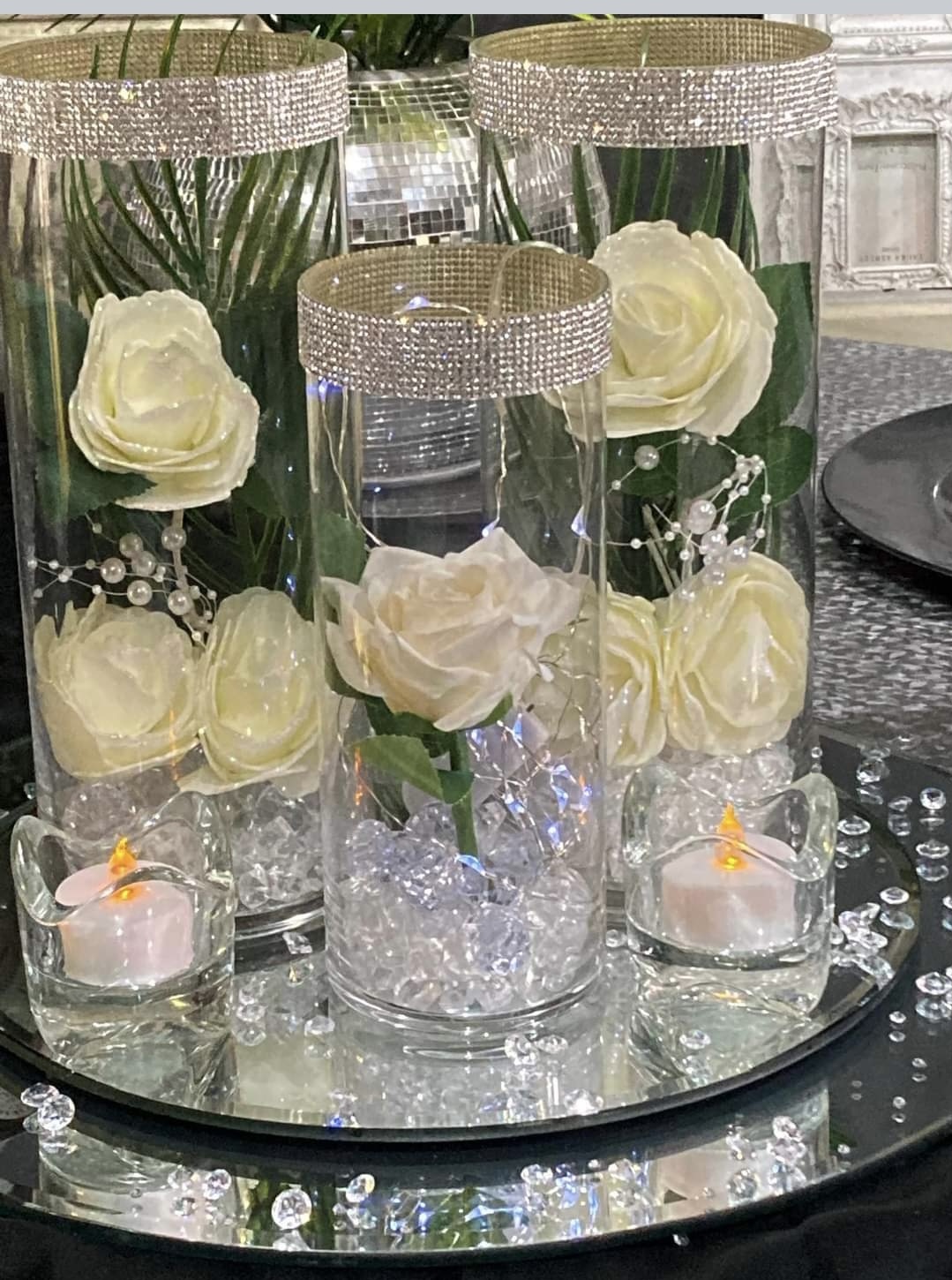 3 glass vases with diamanté rims and filled with white roses