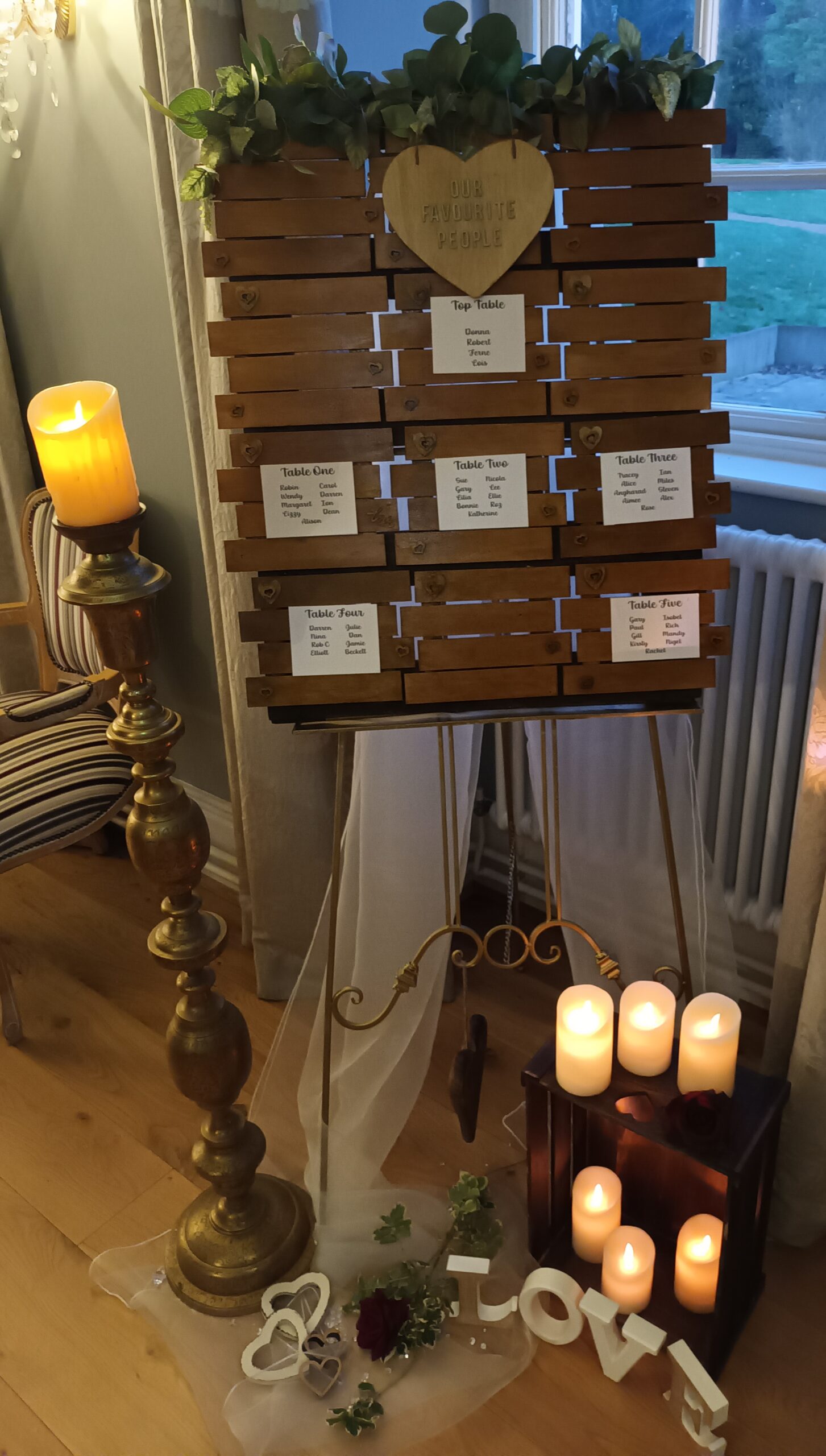 Rustic style seating plan with large metal candlestick and lots of candles around the bottom