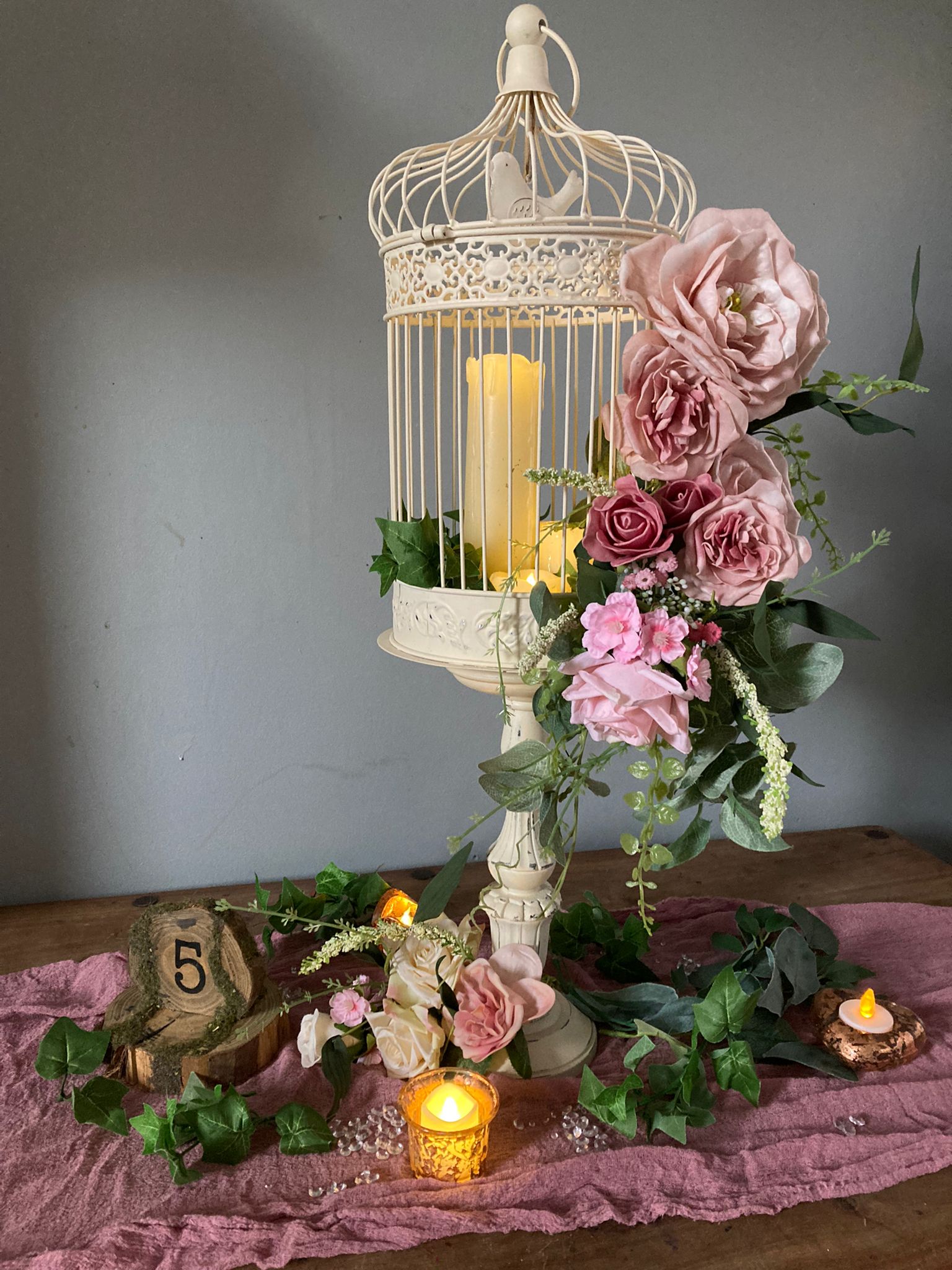 Beautiful bird cage on a stand centrepiece with pink roses