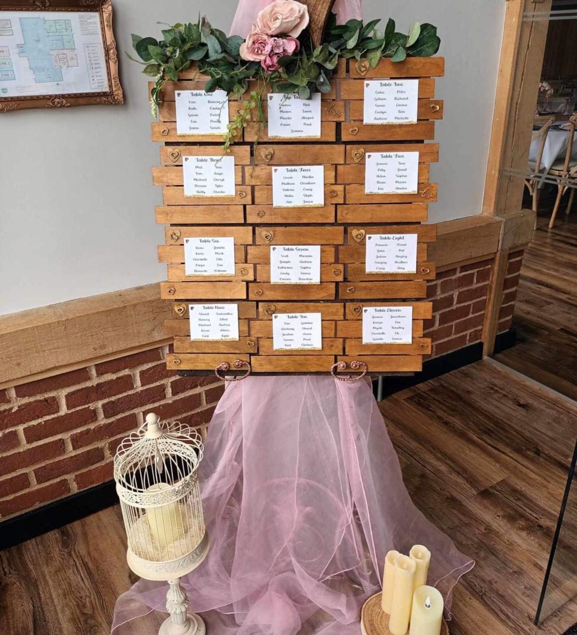 Rustic wooden table plan, with dusky pink swag and roses, with vintage bird cage and candles surrounding