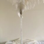 Tall thin glass vase with white feathers