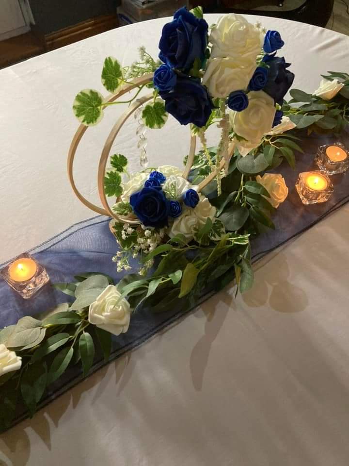 Blue and white flowers on a ring hoop centrepiece on blue runner