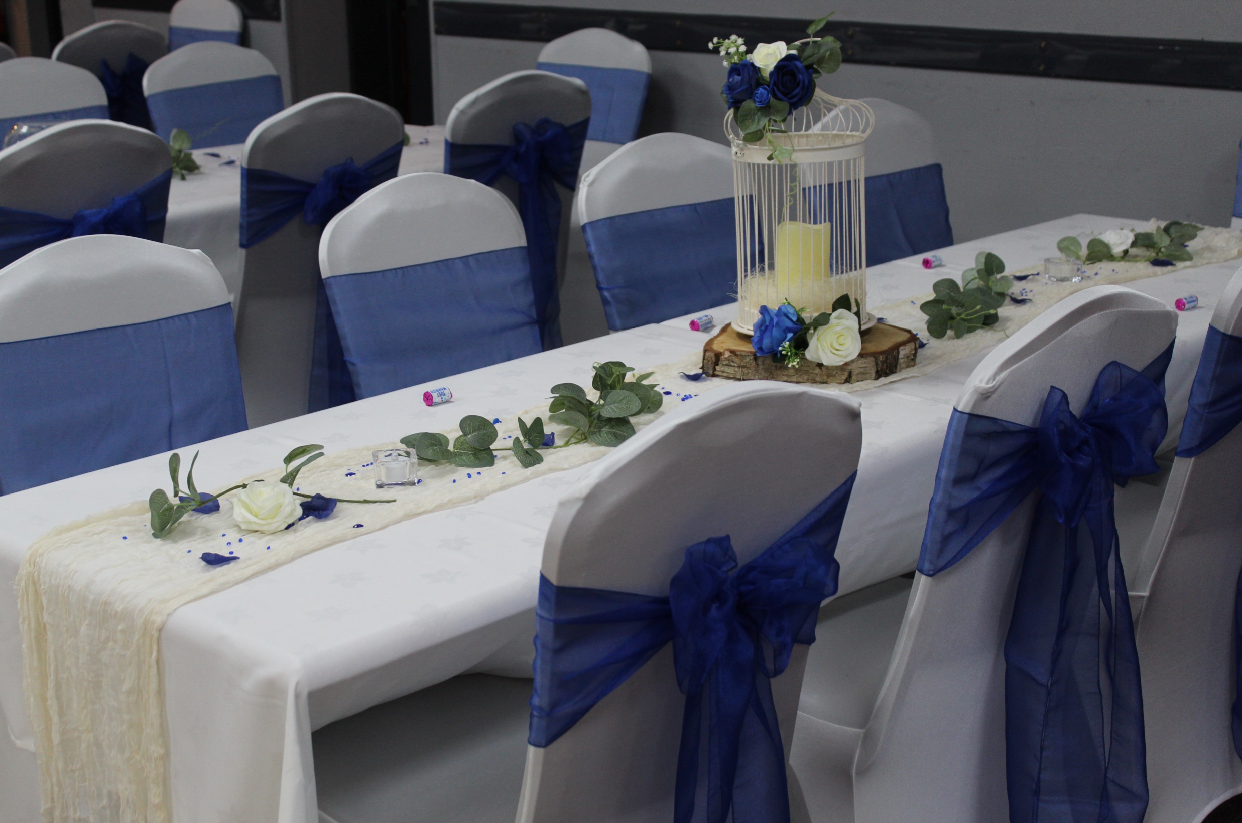Wedding tables and chairs in white with blue sashes
