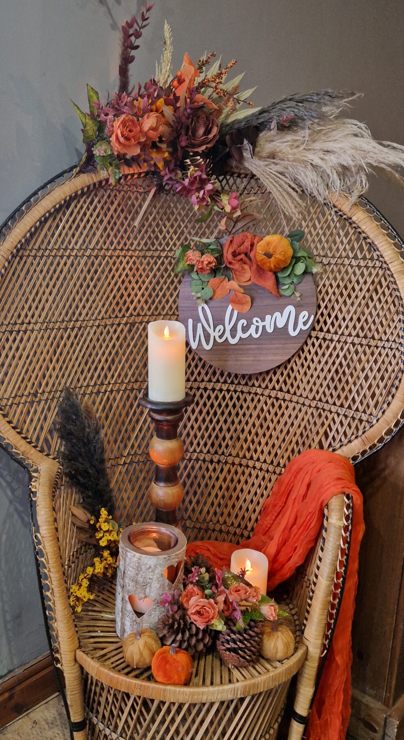 Large peacock chair with wooden welcome sign, rust orange swag and candles