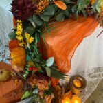 Autumn flower garland hanging down the side of the top table, with candles and pumpkins
