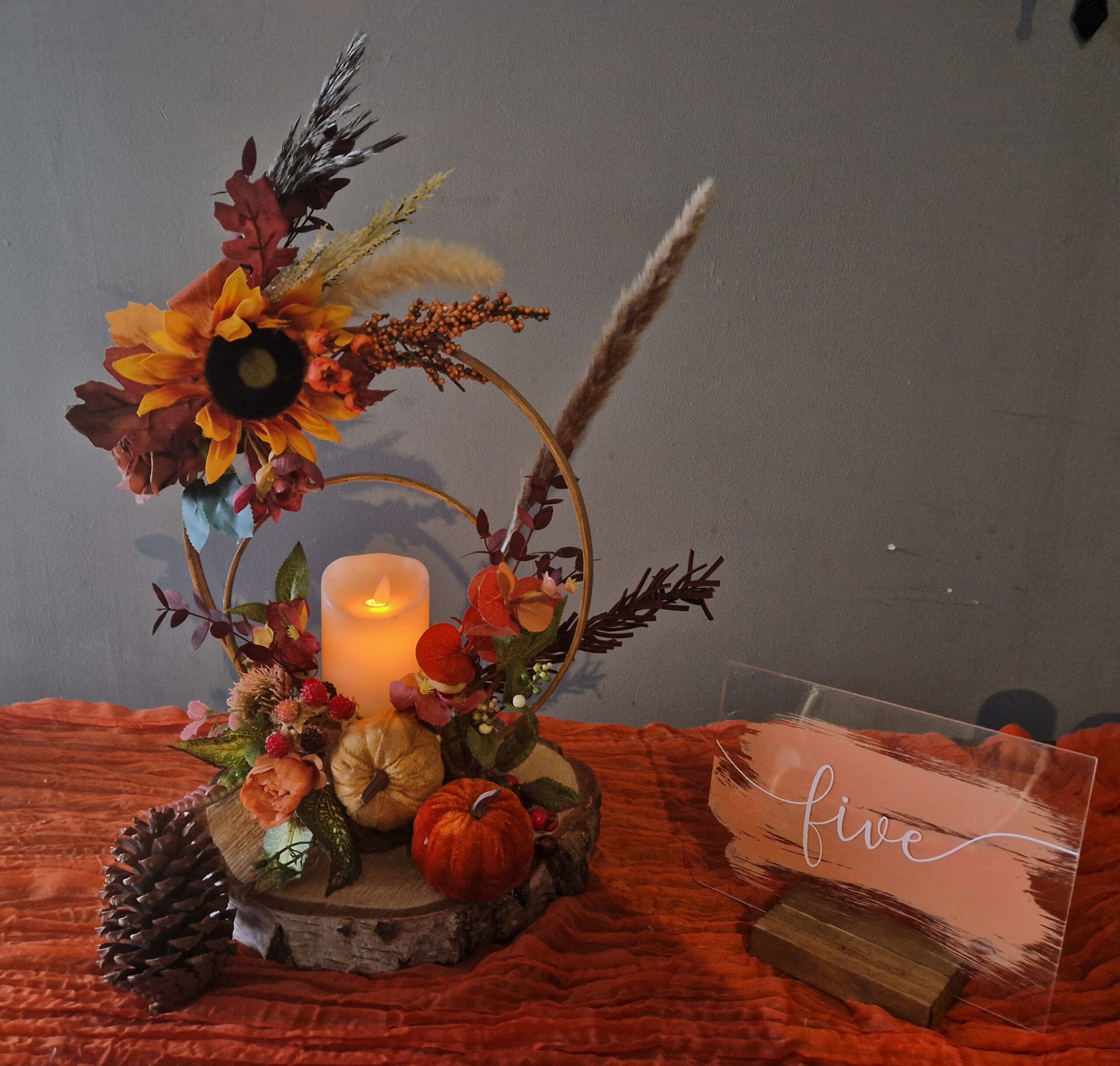 Centrepiece in orange and red colours, wooden rings on a log slice