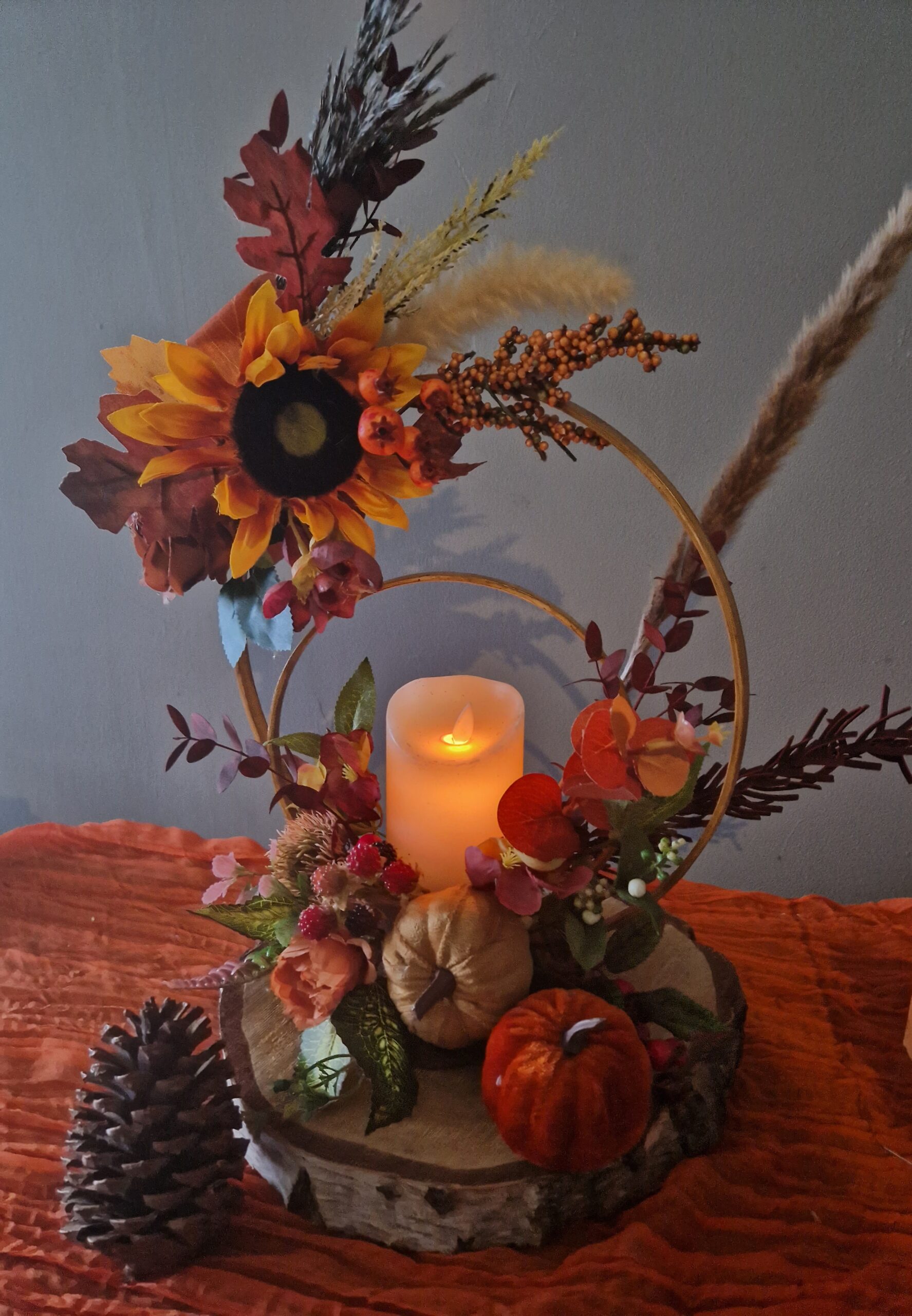 Harvest Moon centrepiece, wooden hoops on a log slice, decorated with autumn colour flowers