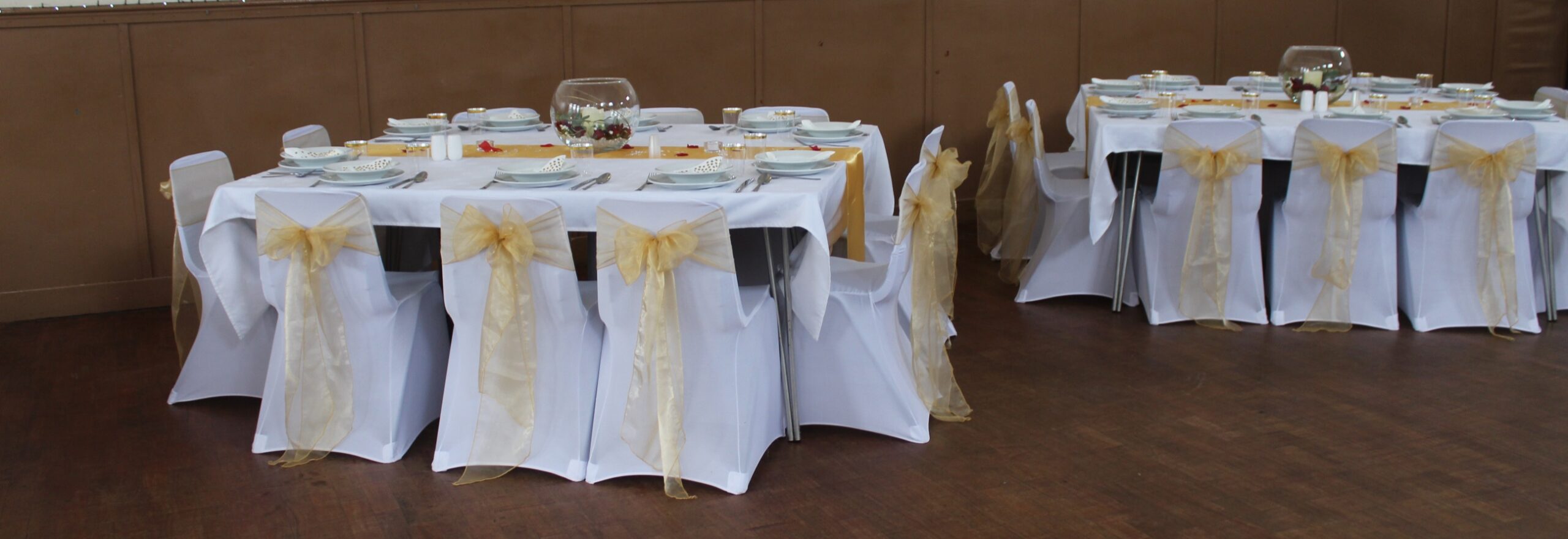 White wedding tables and chairs with gold sashes