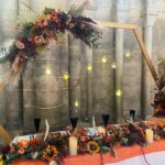 Autumn wedding top table set up, with flower garland, candles and wooden moon gate arch